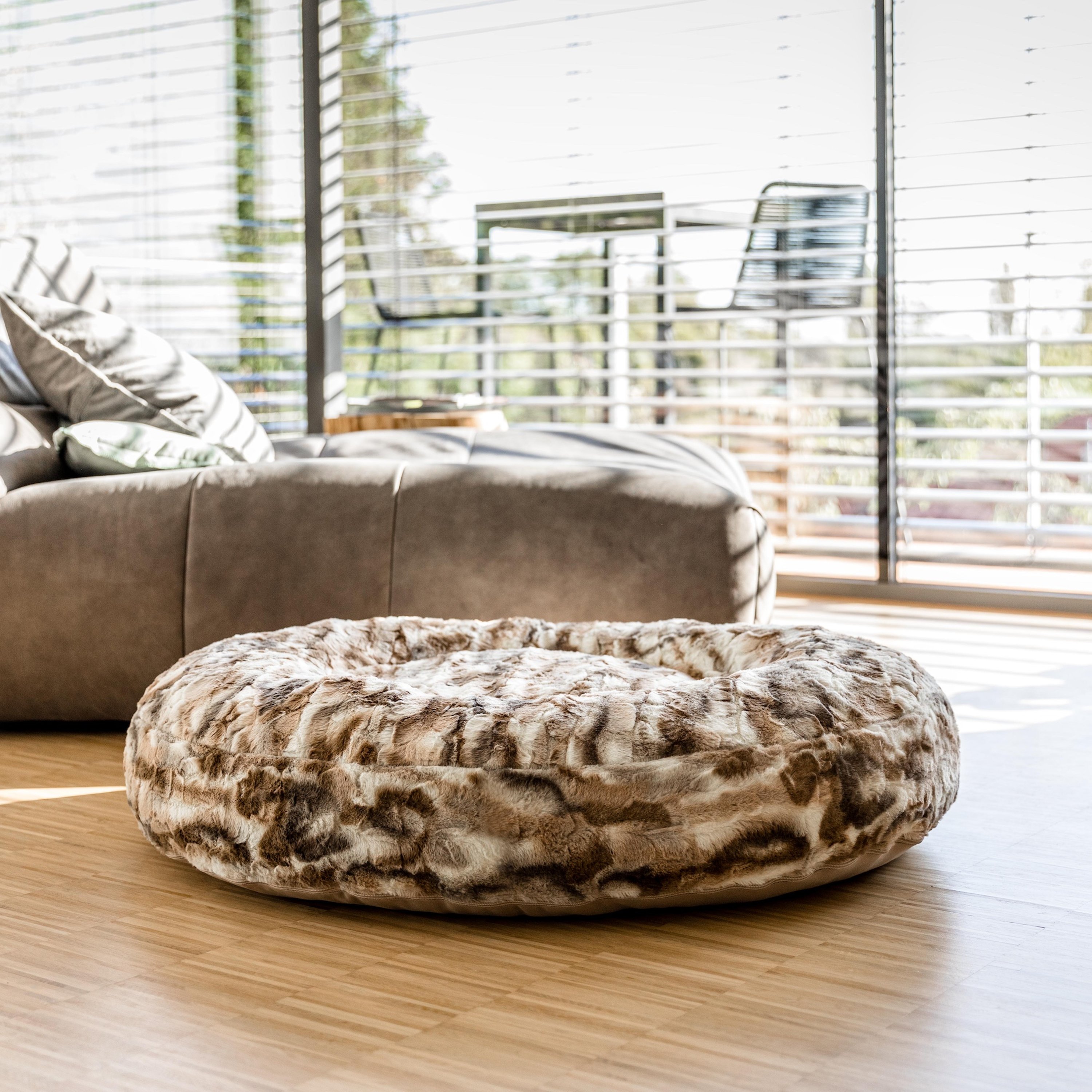Blick auf rundes braun-beiges Hundebett im Wohnzimmer